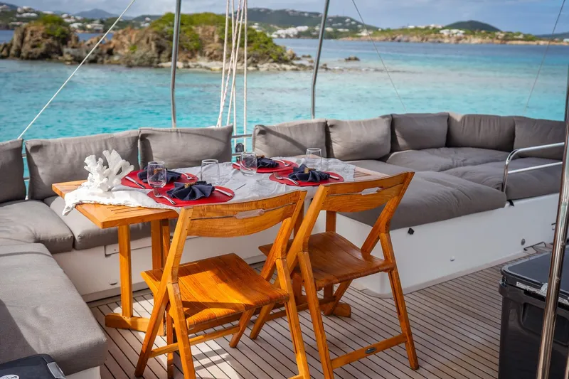 Bluewinds Yacht Photos Pics Luxurious Lagoon 560 S2 yacht deck with dining setup, overlooking serene turquoise waters, 2023 model.