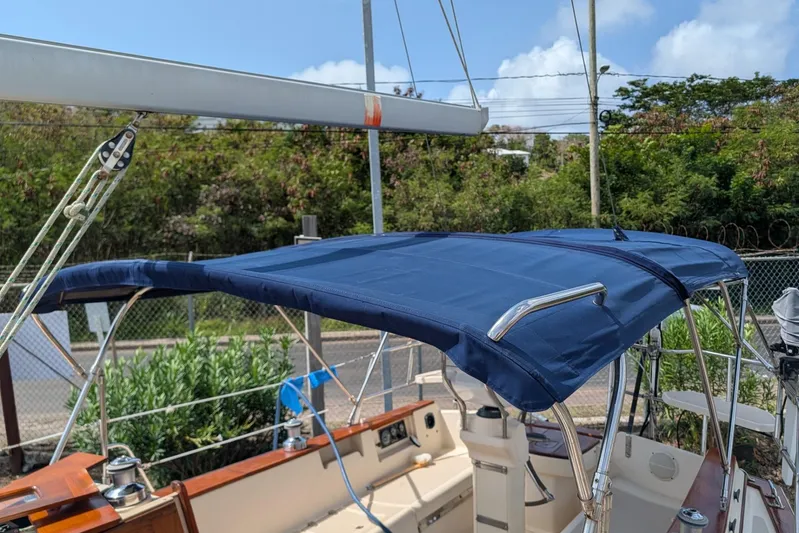 Ivory Star Yacht Photos Pics 1999 Island Packet 350 sailboat with blue bimini top, docked outdoors.