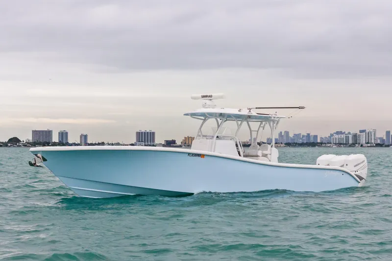  Yacht Photos Pics 2021 Yellowfin 36 Offshore boat cruising on water with city skyline in background.