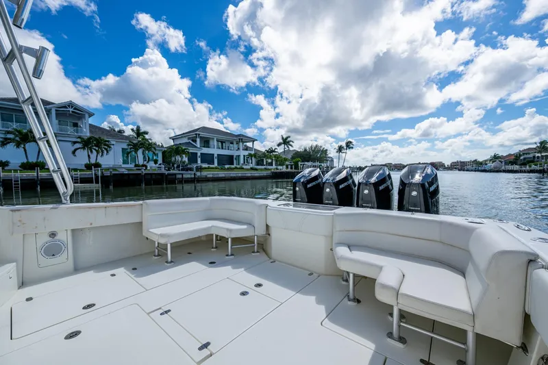 Absent Minded Yacht Photos Pics 2014 SeaVee 430 boat with spacious seating, docked by waterfront homes under a blue sky.