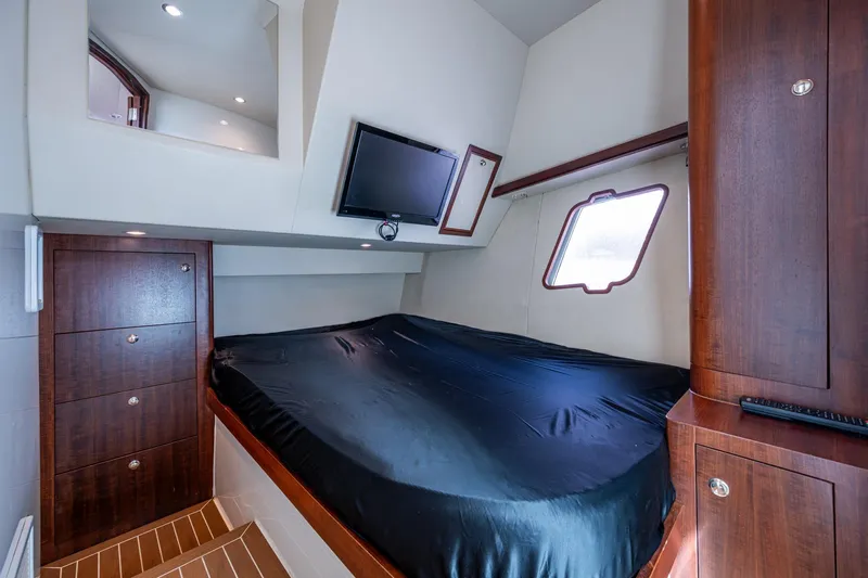 Absent Minded Yacht Photos Pics Luxurious cabin interior of 2014 SeaVee 430 with bed, TV, and wooden cabinetry.