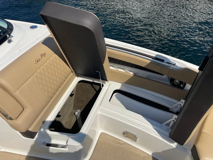  Yacht Photos Pics 2021 Sea Ray SLX 310 boat interior with open storage compartments, beige seating, and water backdrop.
