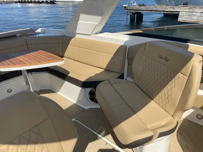  Yacht Photos Pics 2021 Sea Ray SLX 310 boat interior with tan leather seating and wooden table.