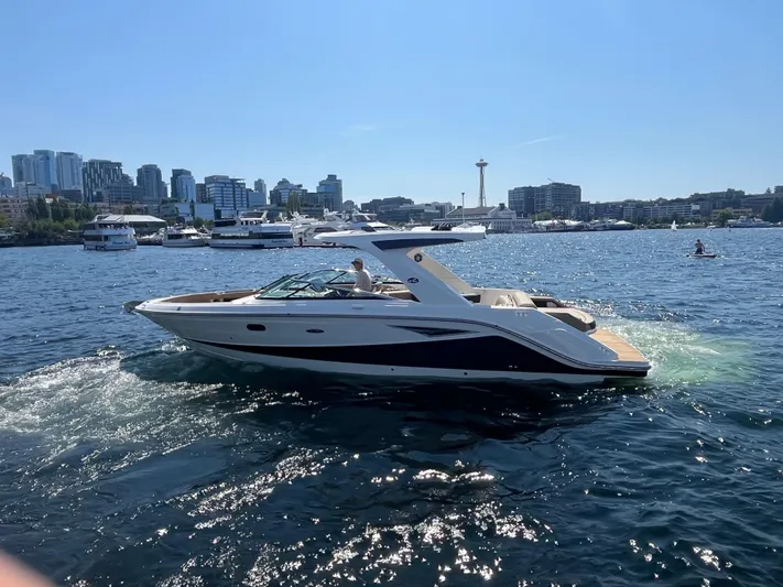  Yacht Photos Pics 2021 Sea Ray SLX 310 boat cruising on a sunny day with city skyline backdrop.
