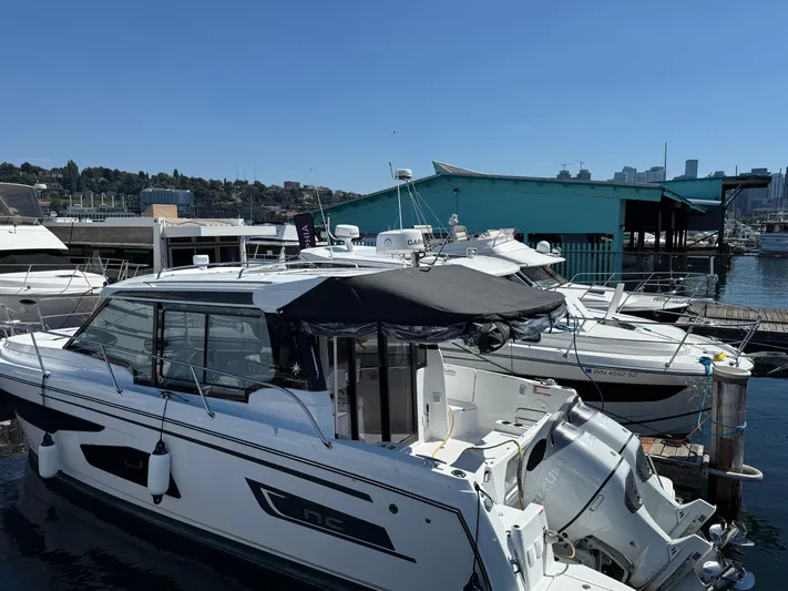  Yacht Photos Pics 2022 Jeanneau NC 1095 Coupe docked at a marina under clear blue skies.