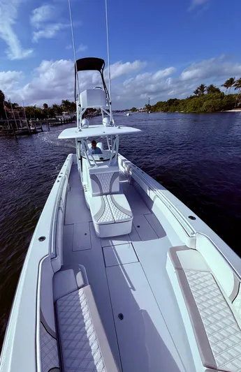  Yacht Photos Pics 2024 Contender 39 ST boat cruising on a scenic waterway under a clear blue sky.