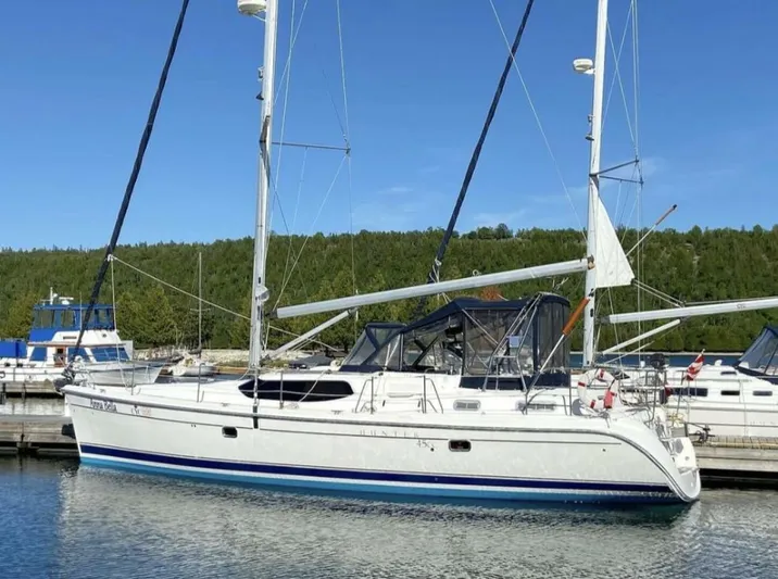  Yacht Photos Pics 2006 Hunter 45 Center Cockpit sailboat docked in a marina, clear blue sky.