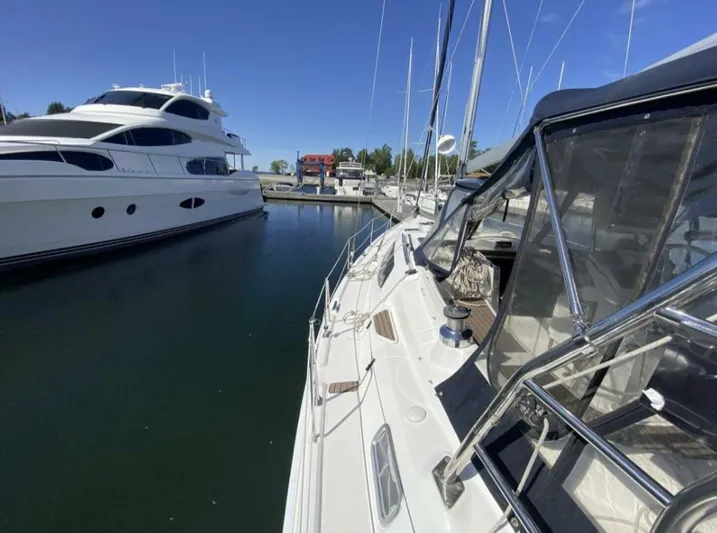  Yacht Photos Pics Hunter 45 Center Cockpit sailboat docked beside a large yacht, clear blue sky.