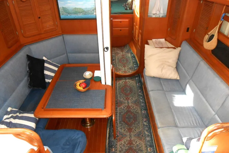 Second Kiss Yacht Photos Pics Cozy interior of 1989 Norseman 447 yacht with blue seating and wooden accents.