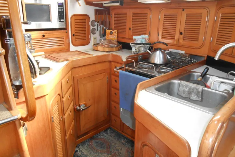 Second Kiss Yacht Photos Pics 1989 Norseman 447 yacht kitchen with wooden cabinets, stove, and sink.