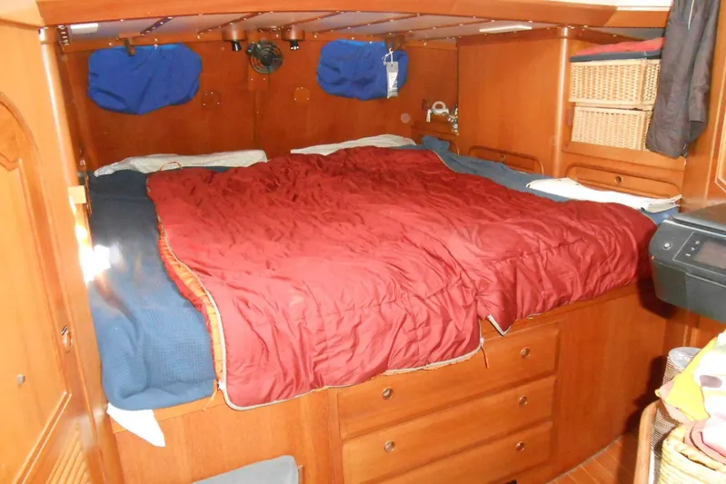 Second Kiss Yacht Photos Pics Cozy cabin interior of 1989 Norseman 447 with red bedding and wooden storage.
