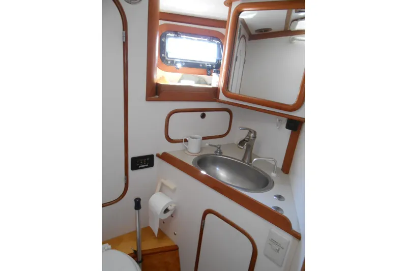 Second Kiss Yacht Photos Pics Compact bathroom in 1989 Norseman 447 yacht with sink, mirror, and porthole window.