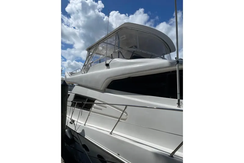 "fortunate" Yacht Photos Pics 1995 JOHNSON 65 Flybridge Motoryacht with sleek design against a cloudy sky backdrop.