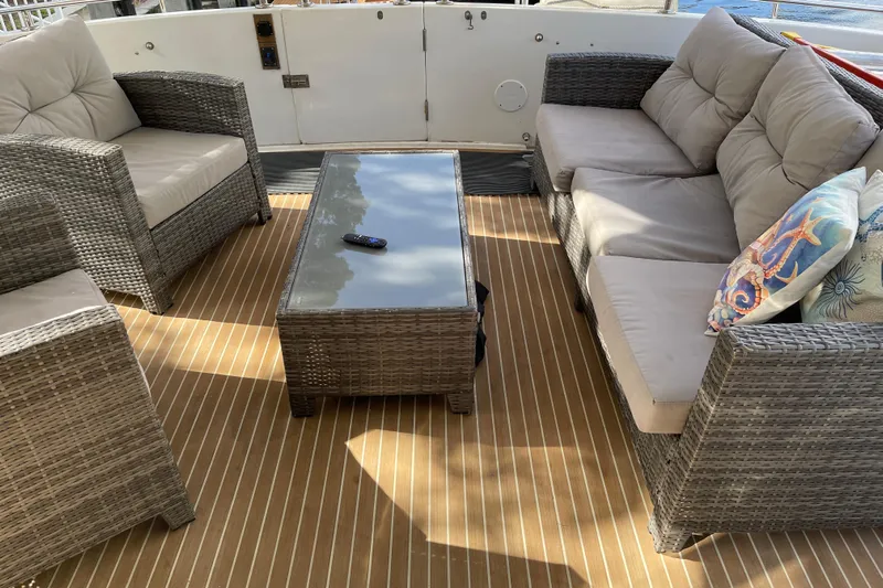 "fortunate" Yacht Photos Pics Outdoor seating area on 1995 JOHNSON 65 Flybridge Motoryacht with wicker furniture and cushions.