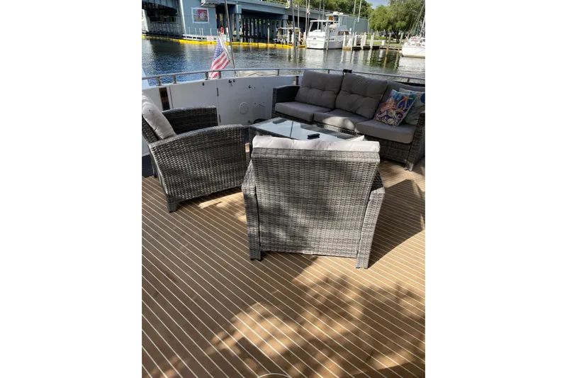 "fortunate" Yacht Photos Pics Outdoor seating on 1995 JOHNSON 65 Flybridge Motoryacht, featuring wicker furniture and waterfront view.
