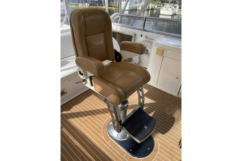 "fortunate" Yacht Photos Pics Captain's chair on 1995 JOHNSON 65 Flybridge Motoryacht, featuring brown leather and metal base.