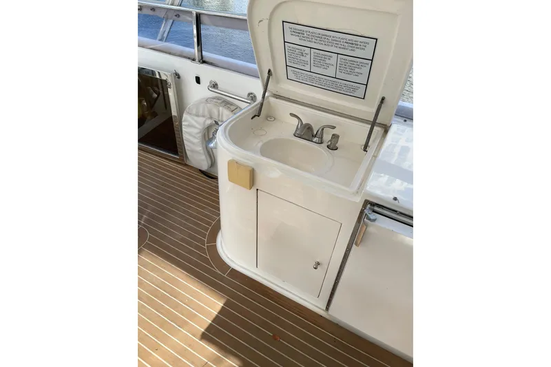 "fortunate" Yacht Photos Pics Flybridge motoryacht sink area on 1995 JOHNSON 65, featuring wooden deck and storage cabinet.