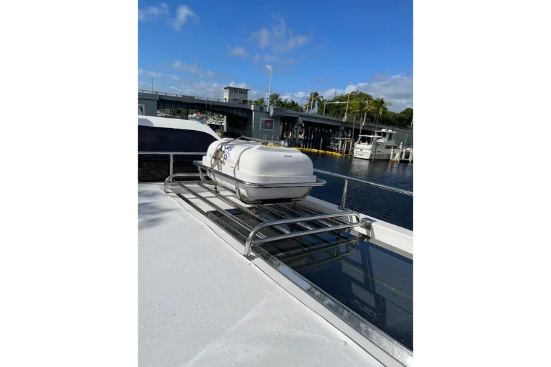 "fortunate" Yacht Photos Pics 1995 JOHNSON 65 Flybridge Motoryacht with life raft on deck, docked near marina.
