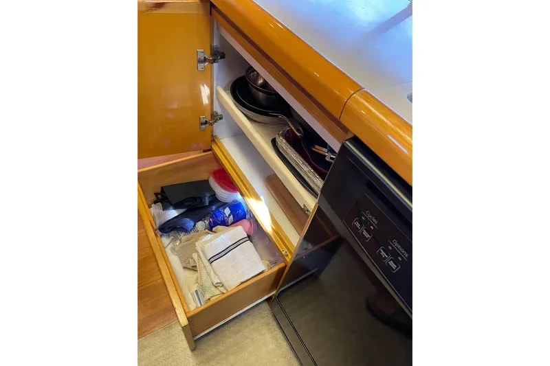 "fortunate" Yacht Photos Pics Open cabinet in 1995 JOHNSON 65 Flybridge Motoryacht kitchen, showing storage and utensils.