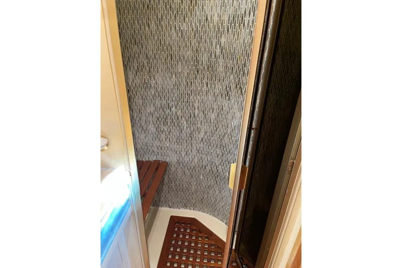 "fortunate" Yacht Photos Pics Shower area in 1995 JOHNSON 65 Flybridge Motoryacht with wooden floor and textured wall.