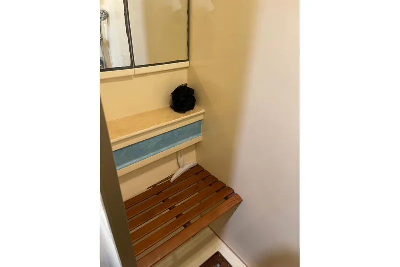 "fortunate" Yacht Photos Pics Bathroom interior of 1995 JOHNSON 65 Flybridge Motoryacht with wooden bench and mirror.