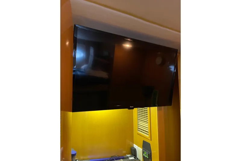 "fortunate" Yacht Photos Pics Flat-screen TV inside 1995 JOHNSON 65 Flybridge Motoryacht, mounted on wooden panel.