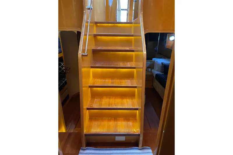 "fortunate" Yacht Photos Pics Illuminated wooden staircase inside 1995 JOHNSON 65 Flybridge Motoryacht, leading to upper deck.