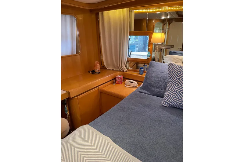 "fortunate" Yacht Photos Pics Cozy cabin interior of 1995 JOHNSON 65 Flybridge Motoryacht with bed and wooden furnishings.