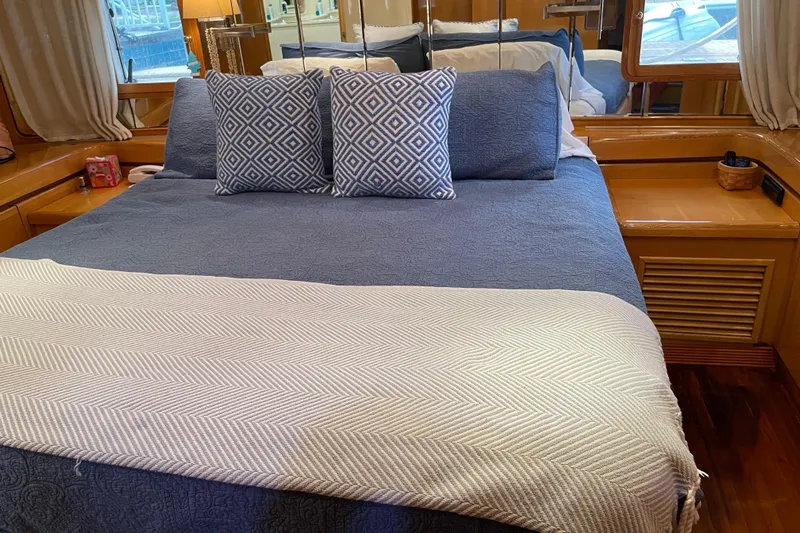 "fortunate" Yacht Photos Pics Luxurious bedroom interior of 1995 JOHNSON 65 Flybridge Motoryacht with blue bedding and patterned pillows.