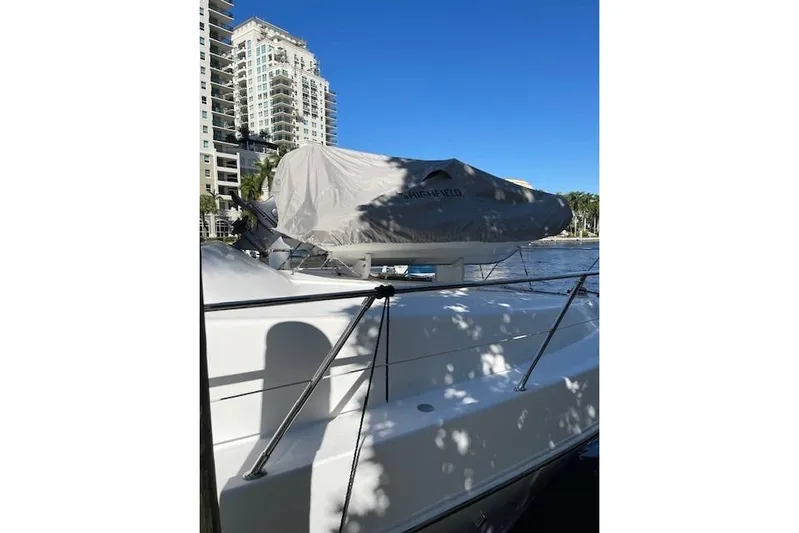 "fortunate" Yacht Photos Pics 1995 Johnson Flybridge Motoryacht docked near high-rise buildings under clear blue sky.