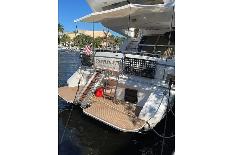 "fortunate" Yacht Photos Pics 1995 Johnson Flybridge Motoryacht docked, featuring a spacious deck and American flag.