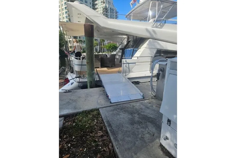 "fortunate" Yacht Photos Pics 1995 Johnson Flybridge Motoryacht docked with boarding ramp and cityscape background.