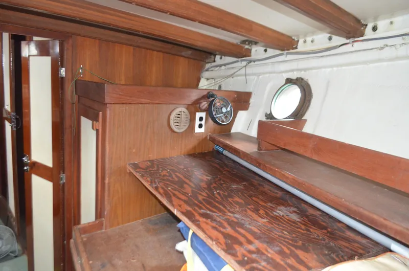 Drakus Yacht Photos Pics Interior of a 1973 Skookum Ketch sailboat with wooden cabinetry and porthole.