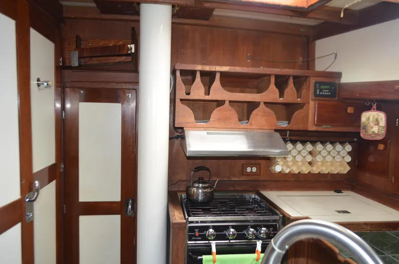 Drakus Yacht Photos Pics 1973 Skookum Ketch kitchen with wooden cabinets, stove, and spice rack.