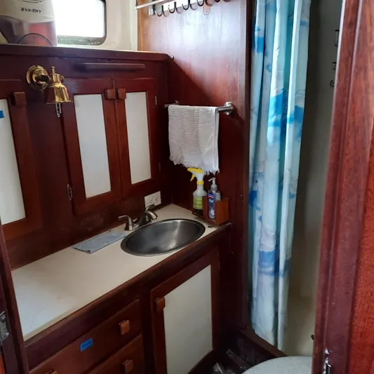 Drakus Yacht Photos Pics 1973 Skookum Ketch bathroom with wooden cabinets, sink, and shower curtain.