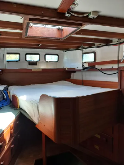 Drakus Yacht Photos Pics Interior of a 1973 Skookum Ketch sailboat with wooden bed and porthole windows.