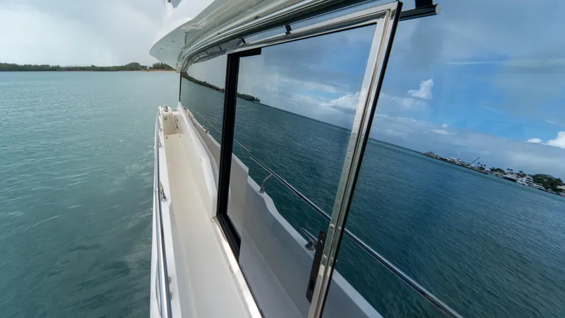 Yachtooma Yacht Photos Pics Side view of 2017 Present Yachts 680 on calm water, reflecting sky and shoreline.