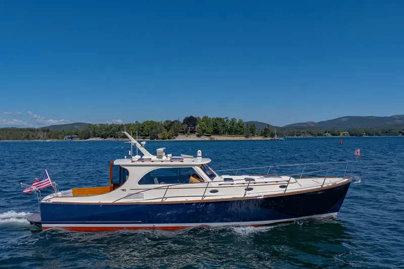 Maine Squeeze Yacht Photos Pics 2009 Hinckley Talaria 44 MY cruising on a scenic lake under a clear blue sky.