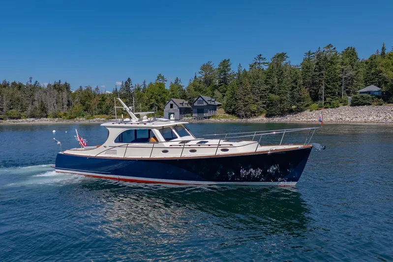 Maine Squeeze Yacht Photos Pics 2009 Hinckley Talaria 44 MY yacht cruising on a serene lake with forested shoreline.