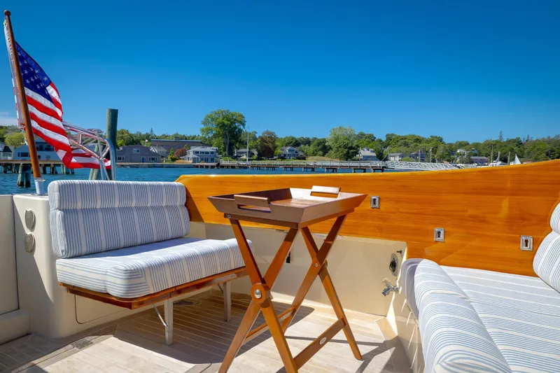 Maine Squeeze Yacht Photos Pics Hinckley Talaria 44 MY 2009 yacht deck with seating, table, and American flag, overlooking marina.