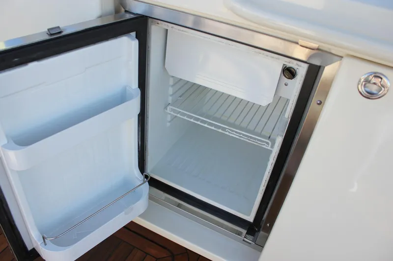 Phoenix Yacht Photos Pics Open mini fridge on 2017 Chris-Craft Launch 38 boat, showcasing interior storage space.