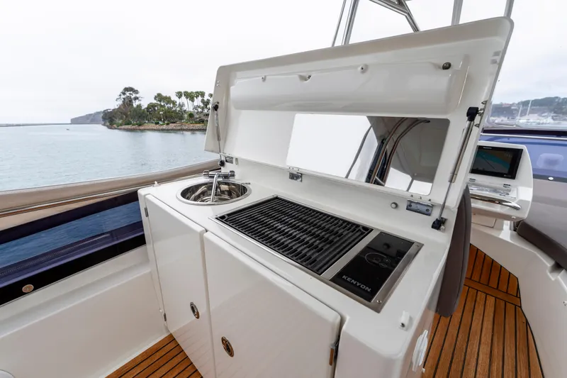 Seeworthy Yacht Photos Pics Outdoor kitchen on 2018 Prestige 560 yacht with grill and sink, overlooking serene waters.