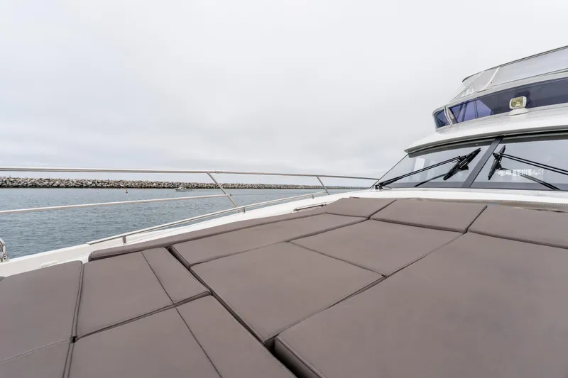 Seeworthy Yacht Photos Pics 2018 Prestige 560 yacht with cushioned deck, overlooking calm waters and breakwater.