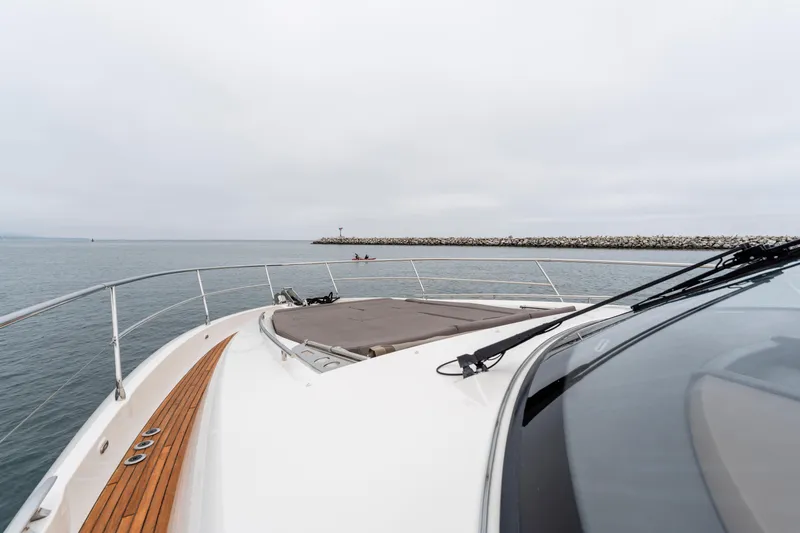 Seeworthy Yacht Photos Pics 2018 Prestige 560 yacht cruising near a rocky breakwater on a cloudy day.