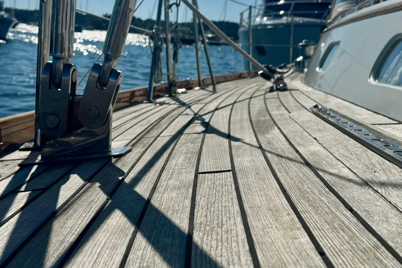 Symphony V Yacht Photos Pics Teak deck of 1999 Hinckley Sou'wester 52 sailboat with metal fittings, sunlit and serene.