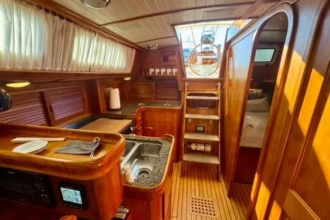 Symphony V Yacht Photos Pics Interior of 1999 Hinckley Sou'wester 52 sailboat with wooden finishes and compact kitchen.