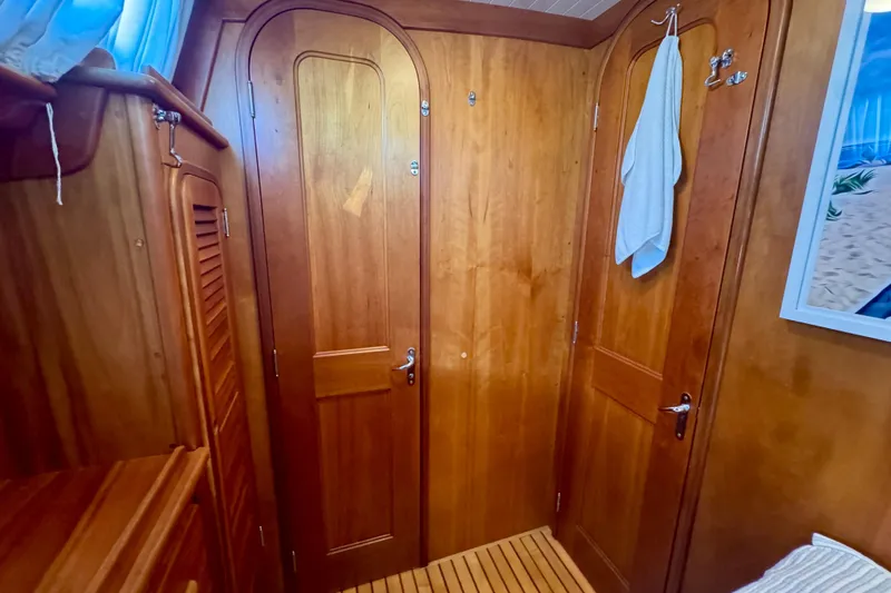 Symphony V Yacht Photos Pics Wood-paneled interior of 1999 Hinckley Sou'wester 52 yacht cabin with doors and towel.