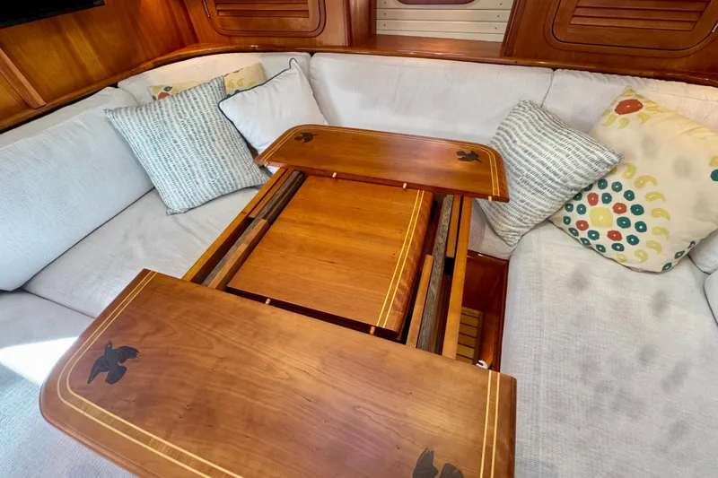 Symphony V Yacht Photos Pics Interior of 1999 Hinckley Sou'wester 52 yacht with wooden table and cushioned seating.