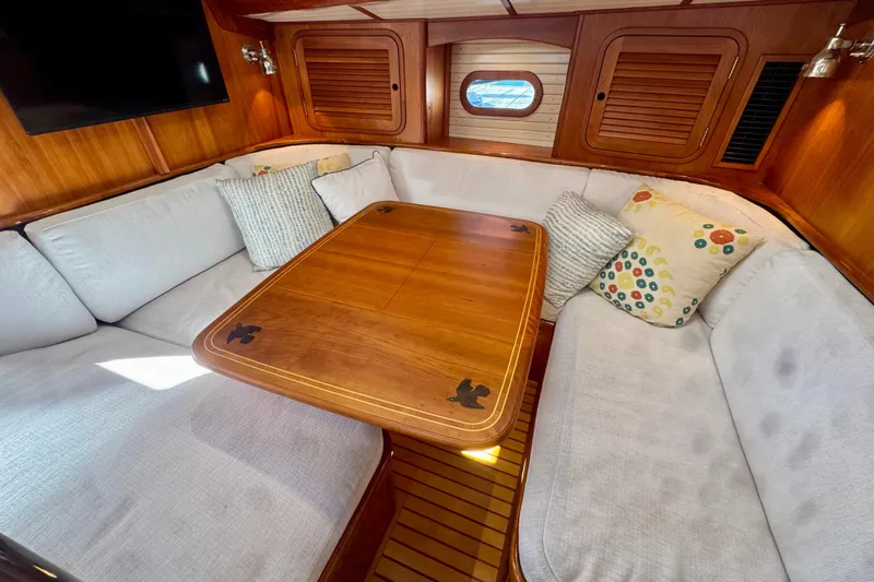 Symphony V Yacht Photos Pics Cozy interior of 1999 Hinckley Sou'wester 52 yacht with wooden table and cushioned seating.