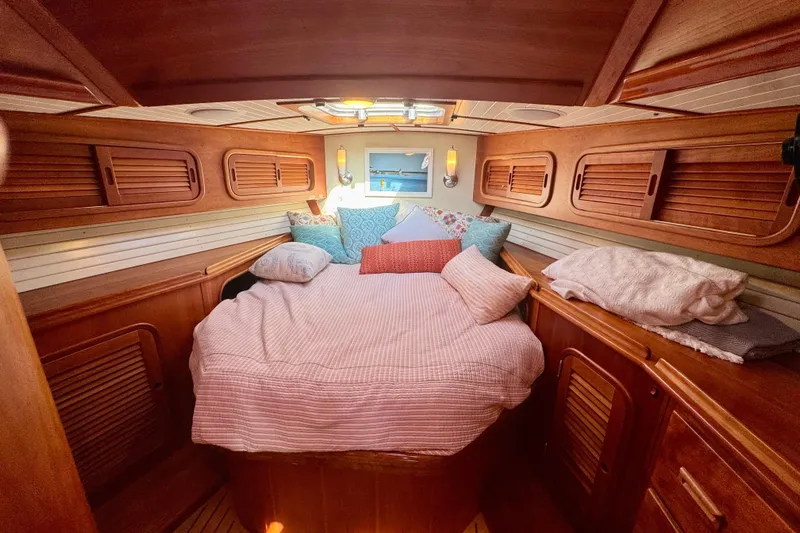 Symphony V Yacht Photos Pics Cozy cabin interior of 1999 Hinckley Sou'wester 52 sailboat with wooden finish and plush bedding.